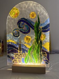 A beautifully crafted glass lamp with vibrant hand-painted designs, glowing warmly to create an artistic ambiance.