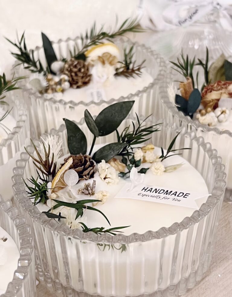 Handmade spice candles in elegant glass jars, adorned with dried flowers, pinecones, and fresh greenery.