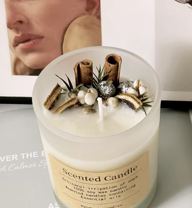 Handcrafted spice candle in a frosted glass jar, featuring cinnamon sticks, dried herbs, and silver accents.
