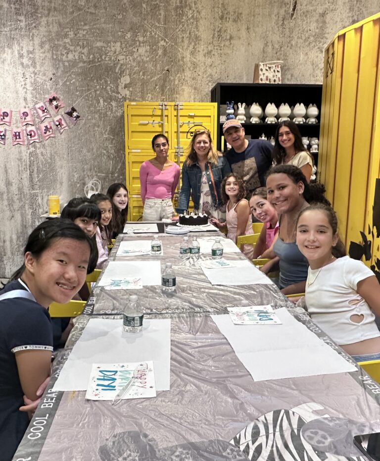 A joyful birthday celebration at Crafts Zone, where kids and families gather around a decorated table for a fun and creative crafting party.