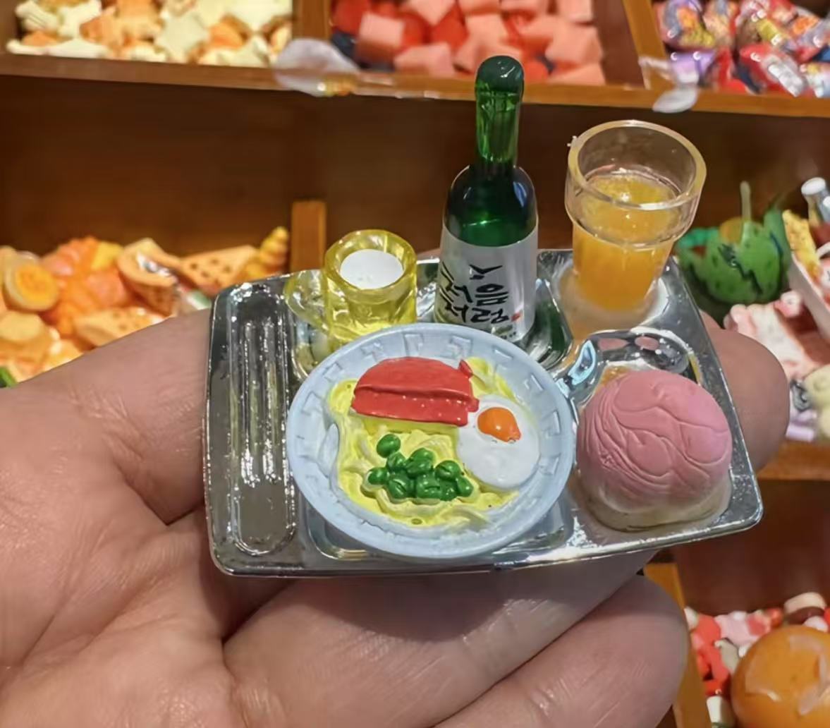 Miniature food tray with noodles, egg, bun, and soju