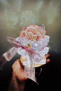 Crystal rose night light made from clear acrylic blocks and pink roses, sitting on a wooden base with LED lighting and a pink ribbon tied around it.