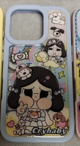 Cute cartoon-style phone case with a teary-eyed girl character labeled "Crybaby", surrounded by plush animals and pastel designs.