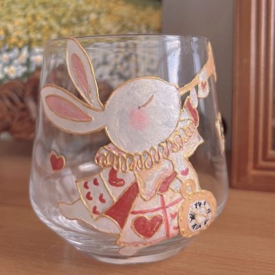A glass cup hand-painted with a cute bunny design, featuring playful details and vibrant colors.