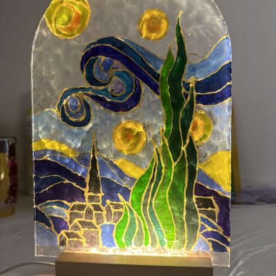 A beautifully crafted glass lamp with vibrant hand-painted designs, glowing warmly to create an artistic ambiance.