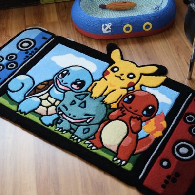 A colorful hand-tufted rug featuring cartoon Pokémon characters Pikachu, Charmander, Squirtle, and Bulbasaur, framed in a Nintendo Switch design on a wooden floor.