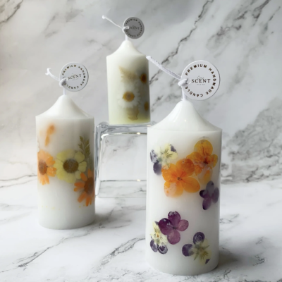 Elegant handmade floral candles featuring embedded dried flowers in a white wax design, crafted for a natural and aesthetic touch.
